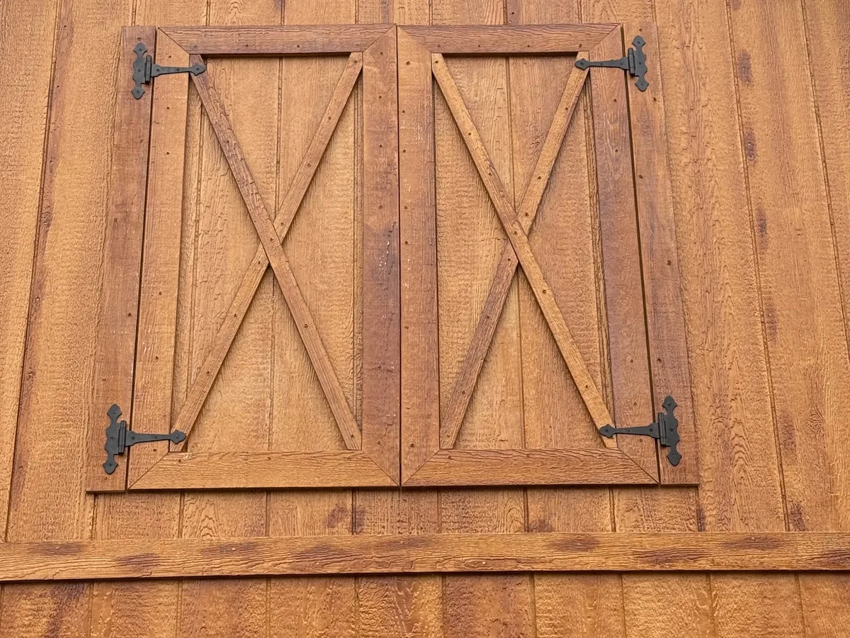 Custom second-floor wooden double doors with X bracing and black strap hinges